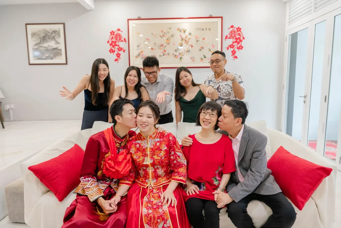 Couple in red qun kua seated with family on a sofa during the morning tea ceremony